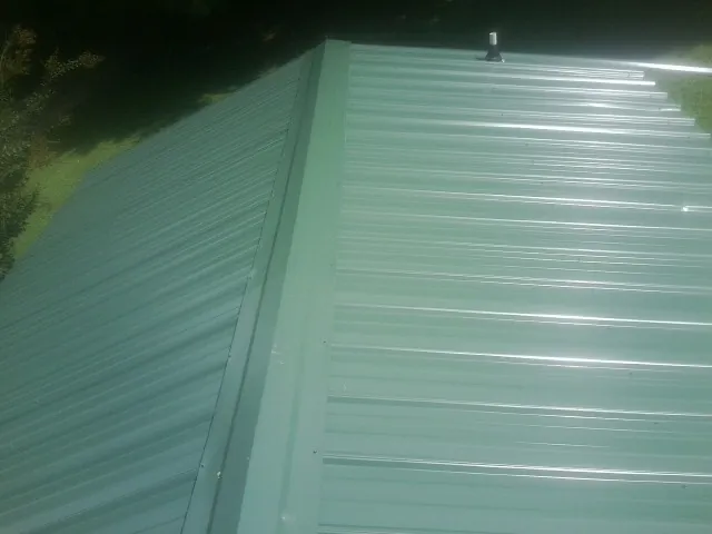 New green metal panels meeting at the ridge of a roof — Flat Roof Repair work by our crew in Armour