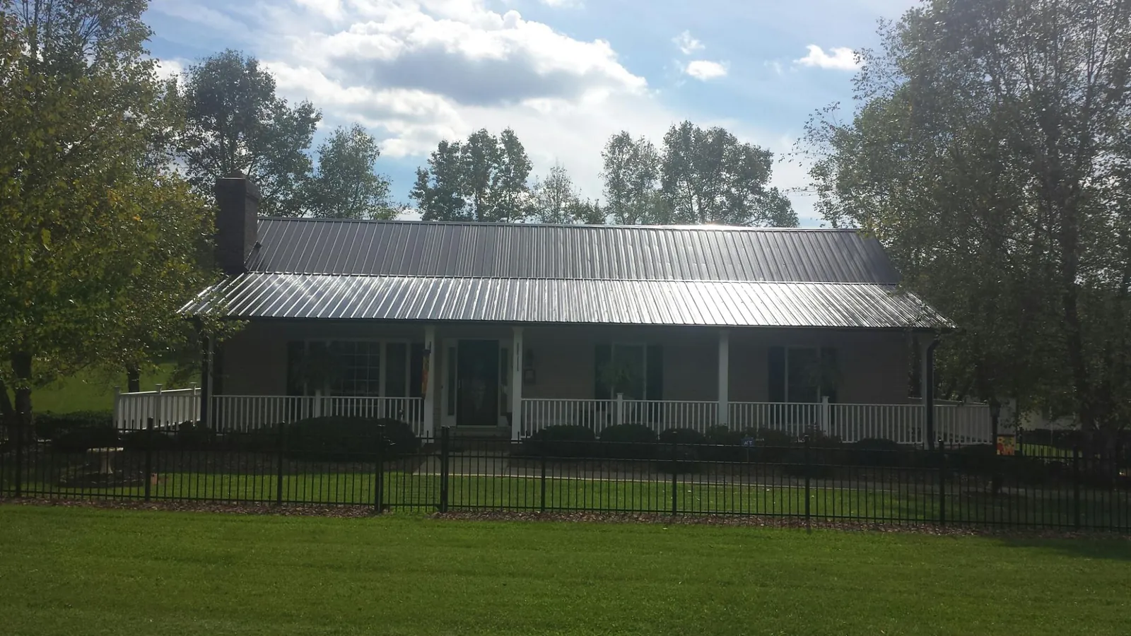 Gray metal roof on a brick ranch with a full width front porch — Gutter Guard Installation work by our crew in Armour