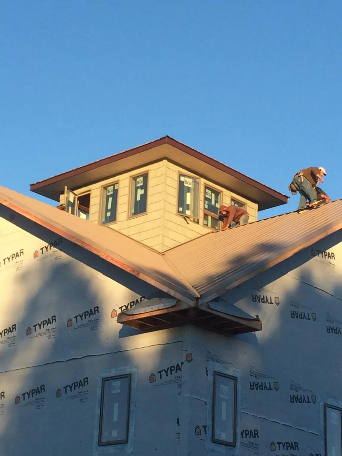 Roofers working around a rooftop cupola on a new metal roof at sunset — Roof Waterproofing in Armour by Roofing Brothers